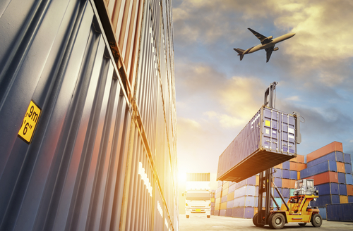 plane flying over a shipping yard