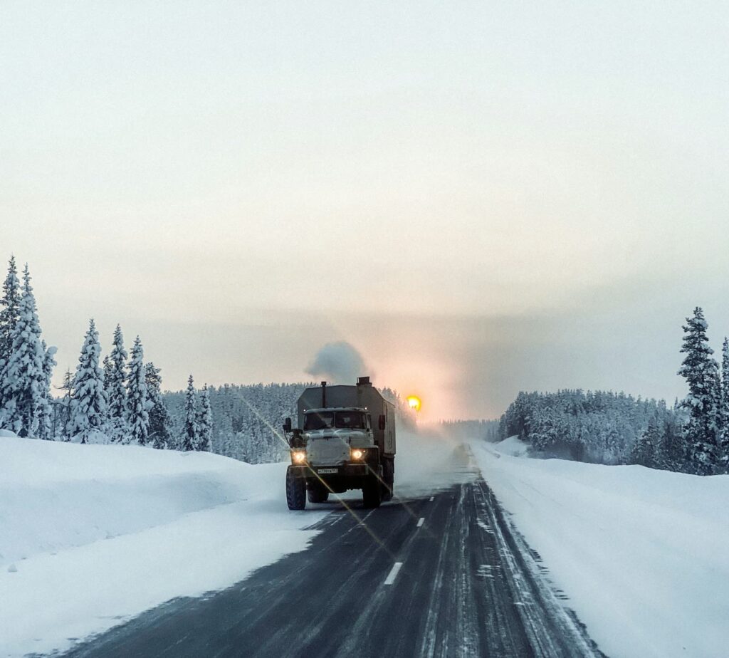 A large truck driving down a snow covered road