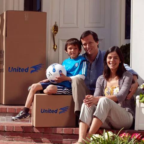 A family sitting on their front steps with United Van Lines moving boxes